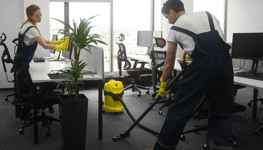 equipo de limpieza aspirando y limpiando oficina